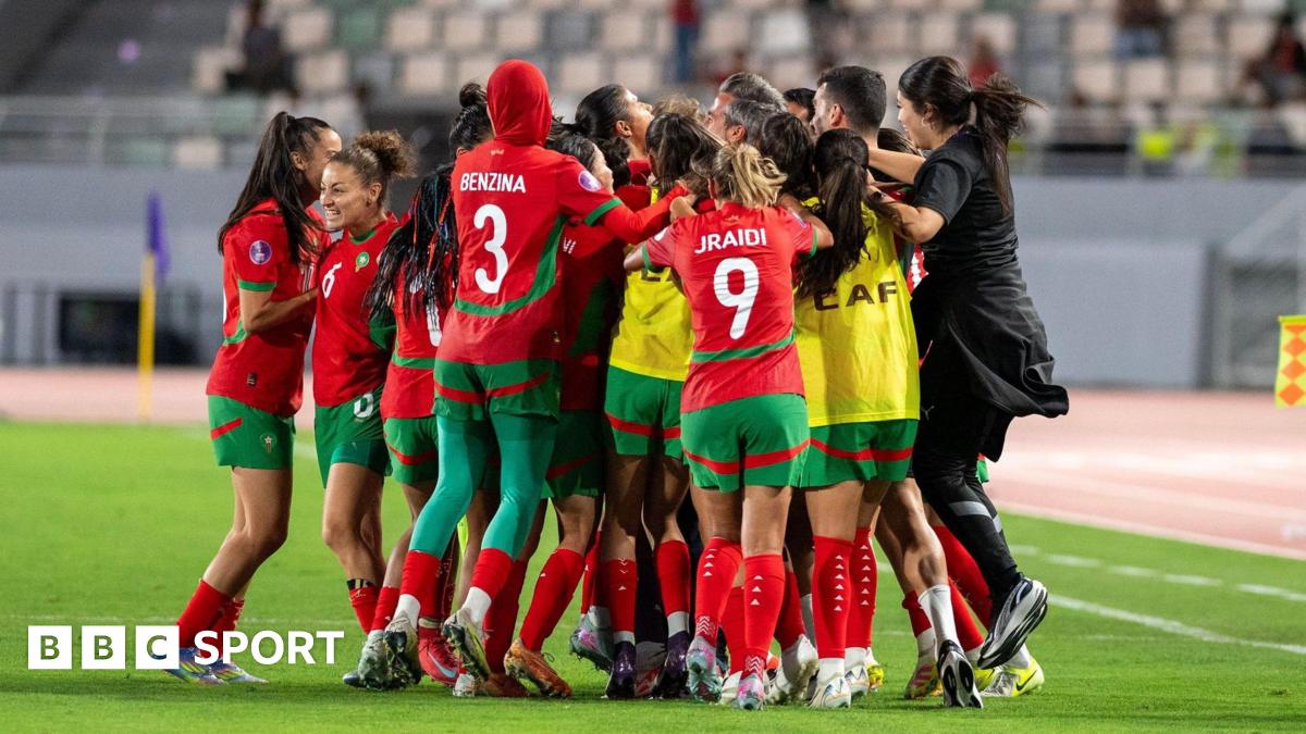 Morocco players and staff celebrate in a huddle on the pitch near the touchline after scoring a late equaliser against Zambia at the 2024 Women